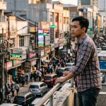 Pria muda mengamati kepadatan aktivitas kawasan urban yang memicu perubahan gaya hidup.